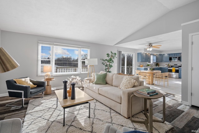 living room featuring vaulted ceiling, ceiling fan, and light hardwood / wood-style flooring