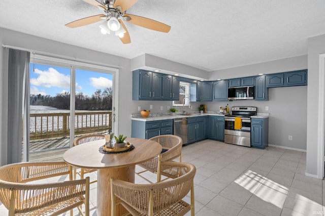 kitchen with blue cabinets, sink, light tile patterned floors, and appliances with stainless steel finishes