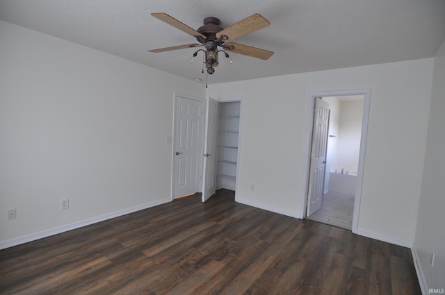 unfurnished bedroom featuring ceiling fan, dark wood-type flooring, ensuite bath, and a closet