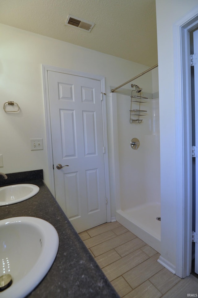 bathroom with vanity, a textured ceiling, and walk in shower