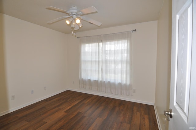 spare room featuring a ceiling fan, dark wood-style flooring, and baseboards