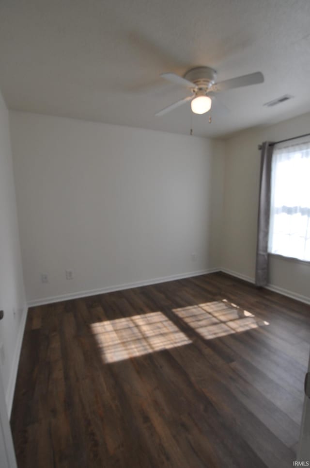 spare room with a ceiling fan, wood finished floors, visible vents, and baseboards