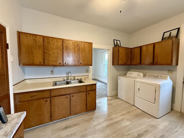 laundry area with separate washer and dryer, sink, cabinets, and light wood-type flooring