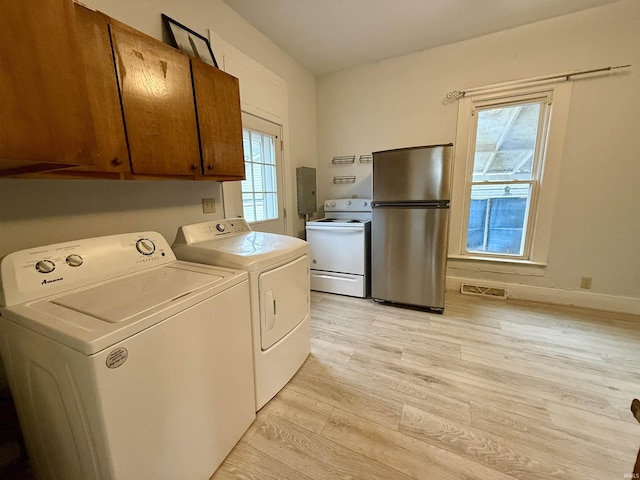 washroom featuring cabinets, separate washer and dryer, and light hardwood / wood-style flooring