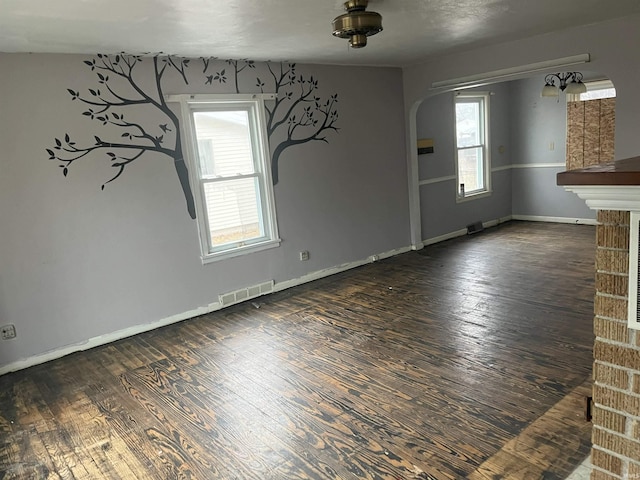 unfurnished living room with dark hardwood / wood-style floors and a wealth of natural light