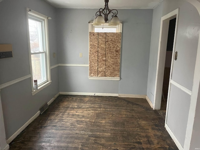 unfurnished dining area featuring dark hardwood / wood-style flooring, a notable chandelier, and a healthy amount of sunlight