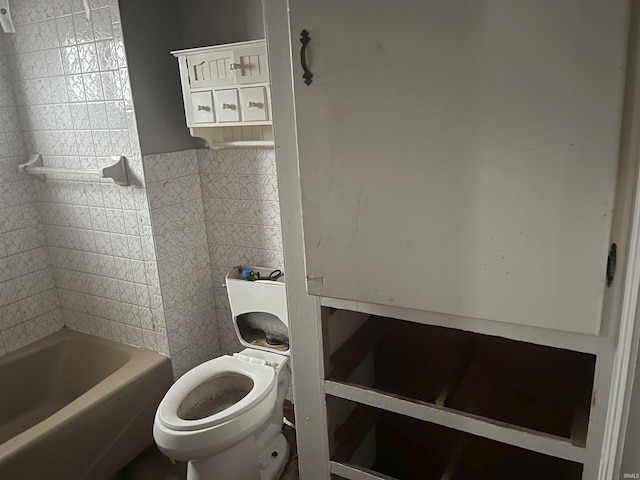 bathroom featuring a bathing tub, tile walls, and toilet