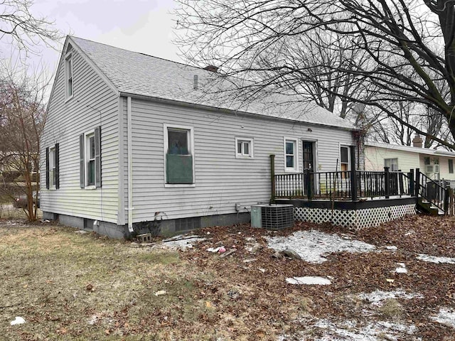 snow covered house with a wooden deck and cooling unit