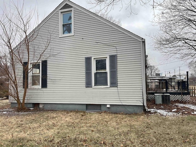 view of side of property featuring a wooden deck, a yard, and central AC unit