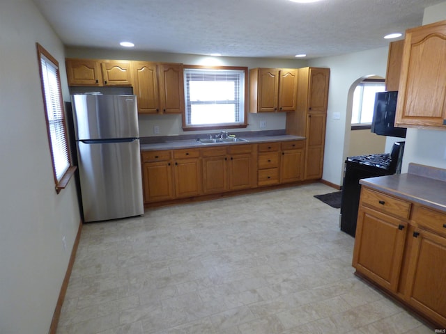 kitchen with range, plenty of natural light, stainless steel fridge, and sink