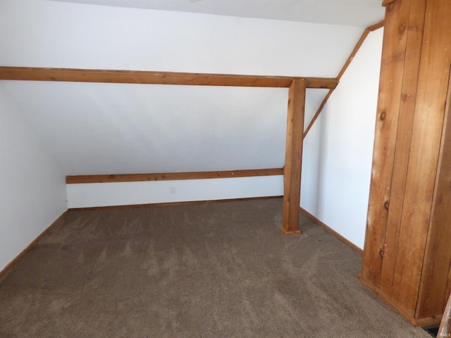 bonus room with dark carpet and vaulted ceiling