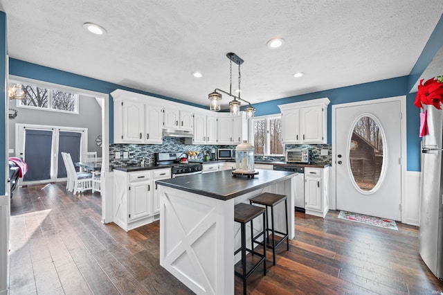 kitchen featuring white cabinetry, dark hardwood / wood-style flooring, stainless steel appliances, and a center island