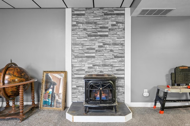 room details featuring carpet floors, a wood stove, and a paneled ceiling