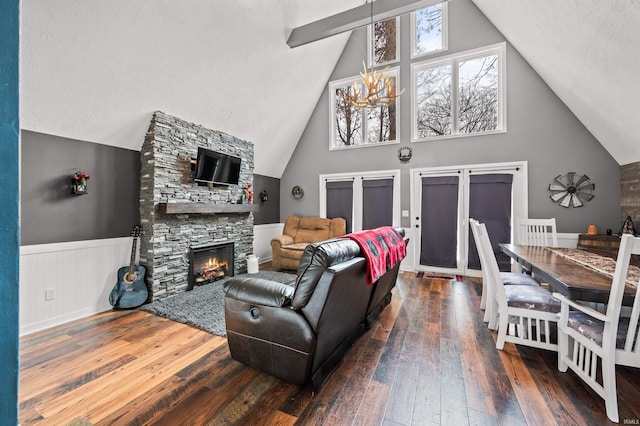 living room with high vaulted ceiling, a fireplace, a textured ceiling, dark hardwood / wood-style flooring, and a chandelier