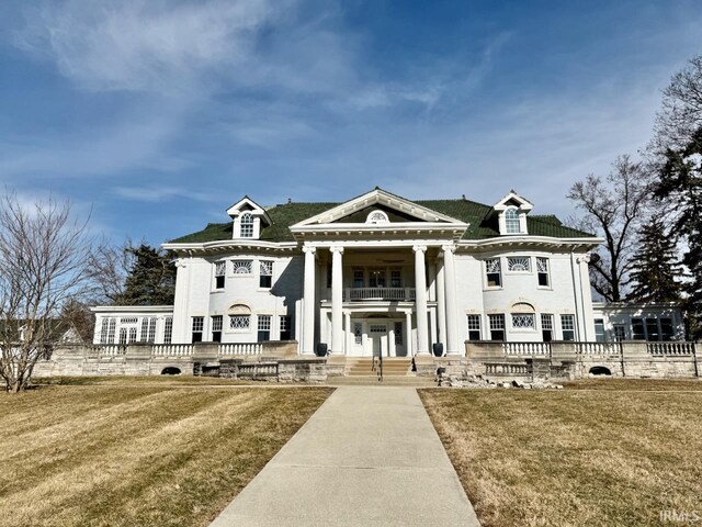 view of front of house featuring a balcony and a front lawn