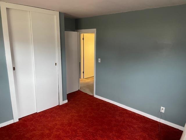 unfurnished bedroom with a closet and dark colored carpet