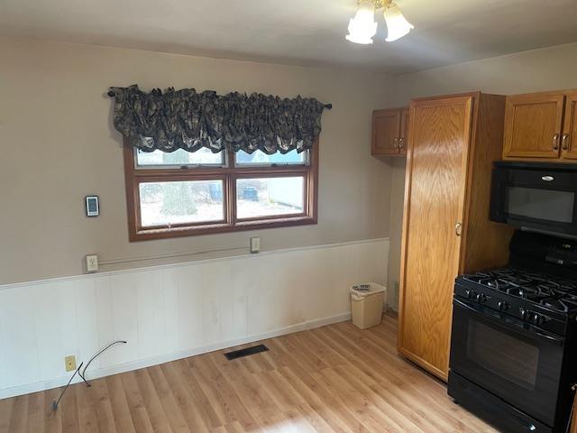 kitchen with black range with gas stovetop and light wood-type flooring