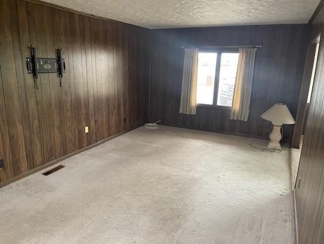 unfurnished room featuring light colored carpet and wooden walls