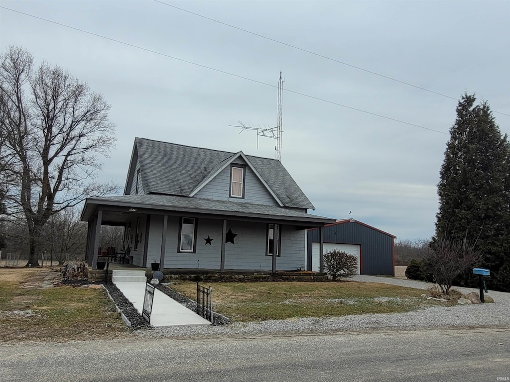 farmhouse with a garage, an outdoor structure, a porch, and a front yard