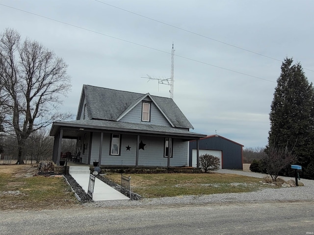 farmhouse with a porch, a garage, an outdoor structure, and a front lawn