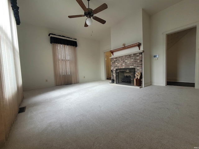 unfurnished living room featuring a high ceiling, a brick fireplace, light carpet, and ceiling fan