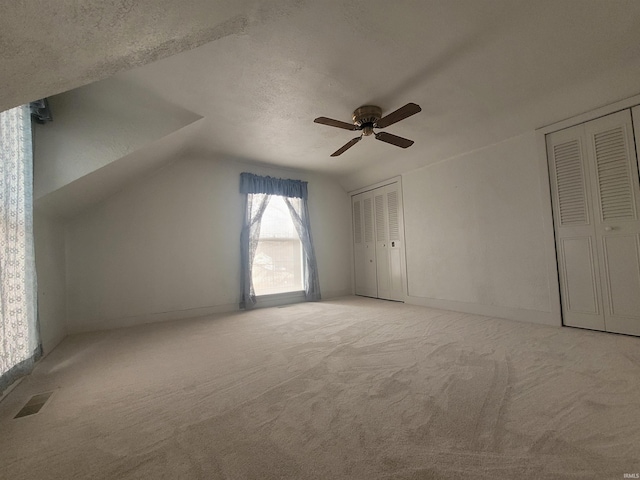 additional living space with ceiling fan, lofted ceiling, carpet floors, and a textured ceiling