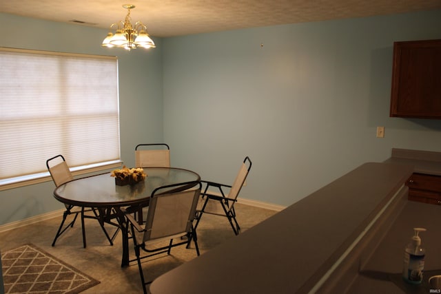 carpeted dining room with an inviting chandelier and a textured ceiling