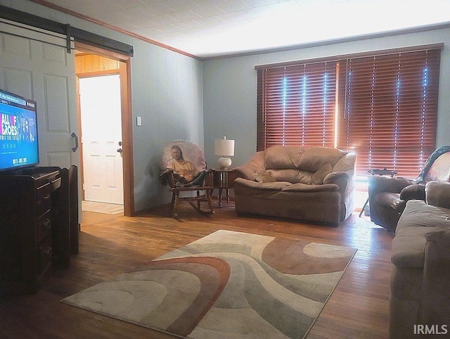 living room featuring wood-type flooring, a barn door, and crown molding