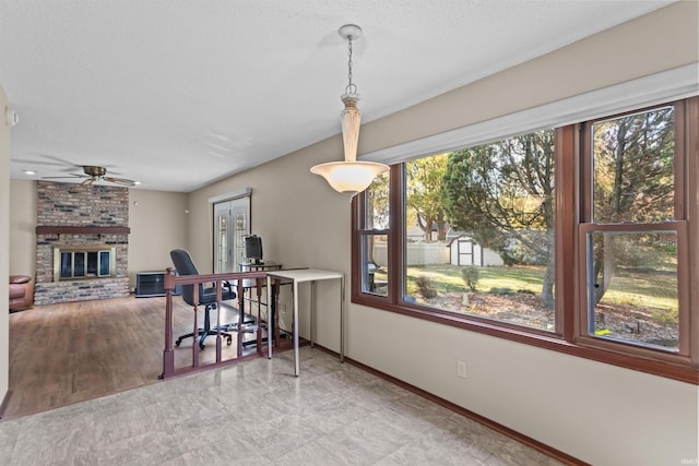 dining area featuring a brick fireplace, a textured ceiling, and ceiling fan