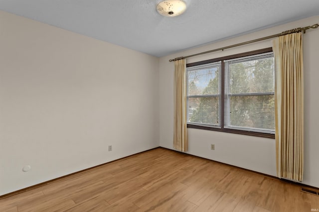 unfurnished room featuring a wealth of natural light, light hardwood / wood-style flooring, and a textured ceiling