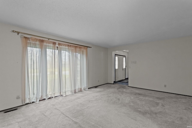 spare room featuring light carpet and a textured ceiling