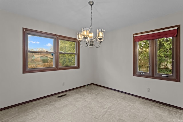 spare room with a wealth of natural light and an inviting chandelier