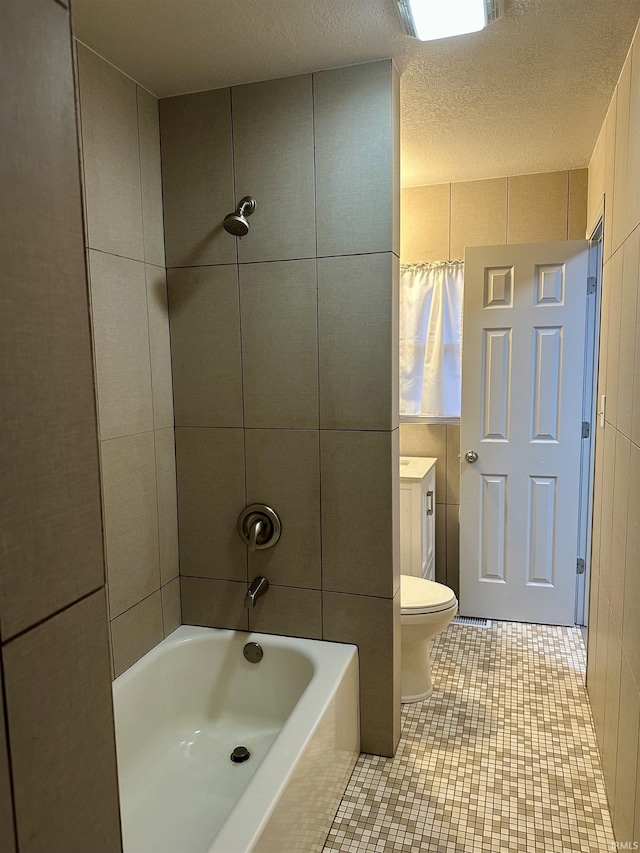 full bathroom with vanity, tiled shower / bath combo, a textured ceiling, and toilet