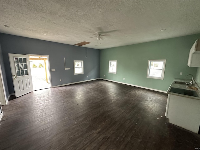 unfurnished living room featuring dark hardwood / wood-style flooring, sink, a textured ceiling, and ceiling fan