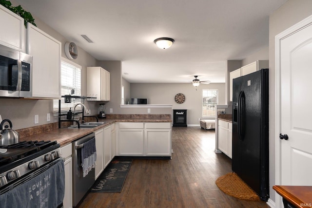 kitchen with sink, dark wood-type flooring, appliances with stainless steel finishes, white cabinetry, and kitchen peninsula