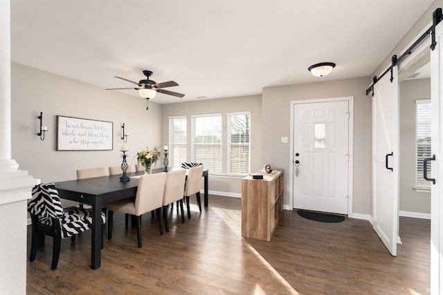 dining room with dark hardwood / wood-style floors, a barn door, and ceiling fan