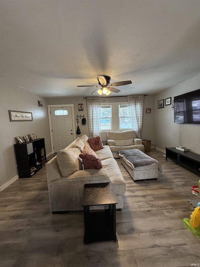 living room with a textured ceiling, dark wood-type flooring, and ceiling fan