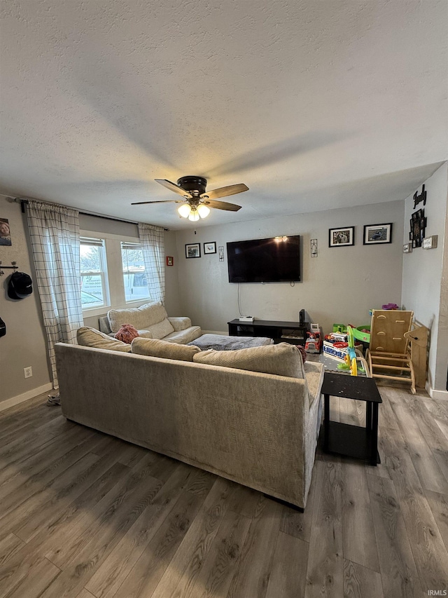 living room with hardwood / wood-style flooring, ceiling fan, and a textured ceiling