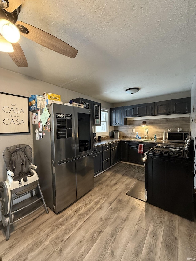 kitchen featuring stainless steel refrigerator, a textured ceiling, range with gas cooktop, and light wood-type flooring