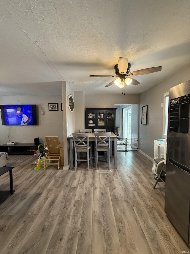 dining space featuring ceiling fan, wood-type flooring, and a textured ceiling