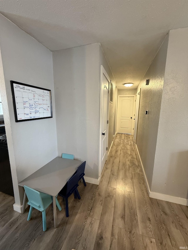 hallway with light hardwood / wood-style flooring and a textured ceiling