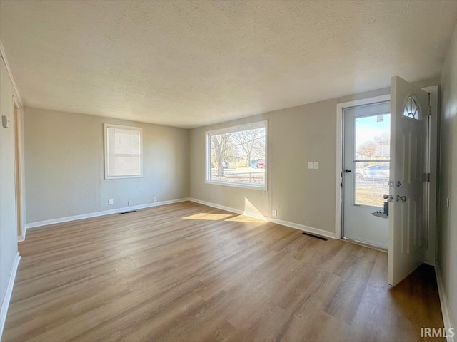 interior space featuring plenty of natural light, light hardwood / wood-style floors, and a textured ceiling