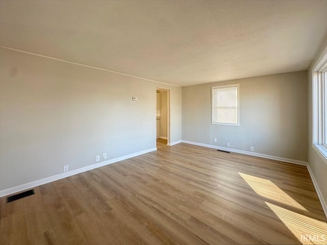 empty room featuring a textured ceiling and light wood-type flooring