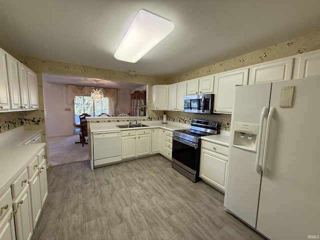 kitchen with white cabinetry, stainless steel appliances, kitchen peninsula, and sink