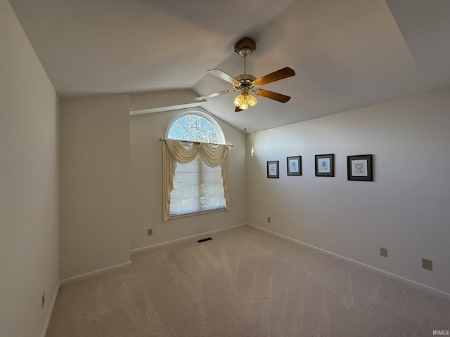 spare room with light carpet, vaulted ceiling, and ceiling fan