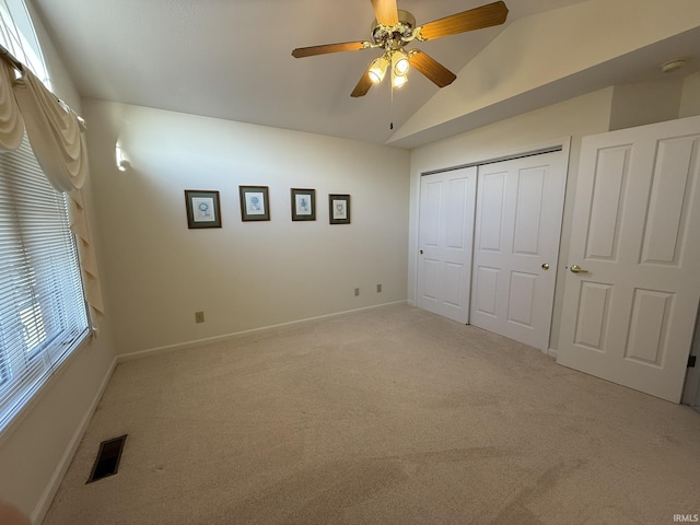 unfurnished bedroom with ceiling fan, a closet, vaulted ceiling, and light carpet