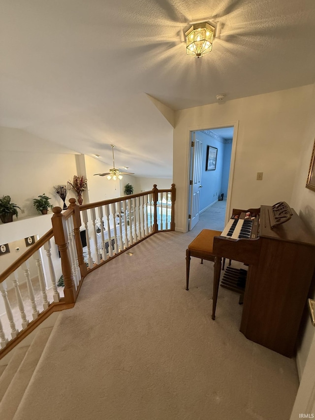 hallway featuring vaulted ceiling, light carpet, and a textured ceiling