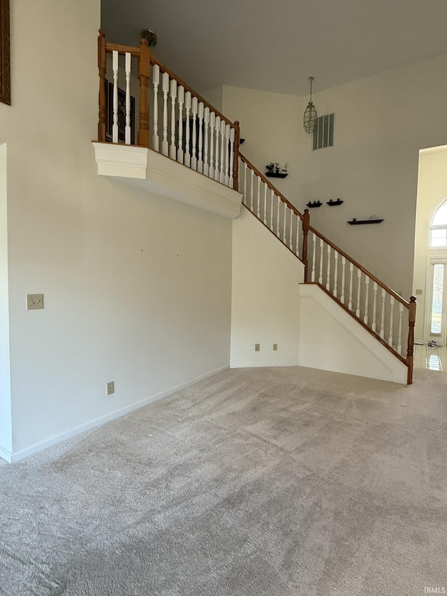 unfurnished living room with carpet floors and a high ceiling