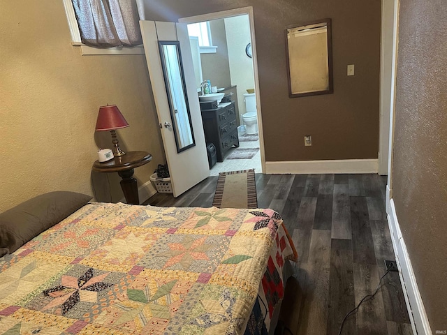 bedroom with ensuite bath and dark wood-type flooring