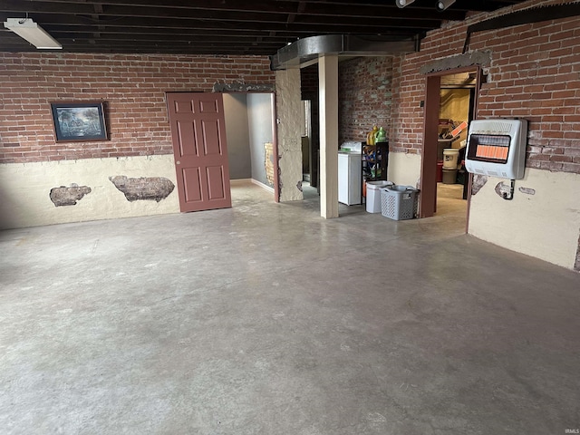 basement featuring heating unit, washer / dryer, and brick wall